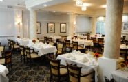 White linen adorned tables with colorful fresh flowers in dining room