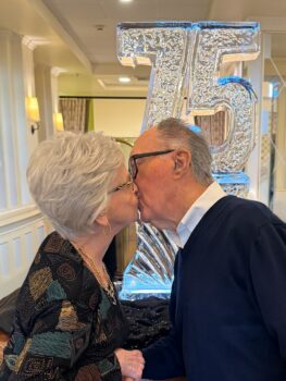 Senior couple kissing at their 75th wedding anniversary celebration.