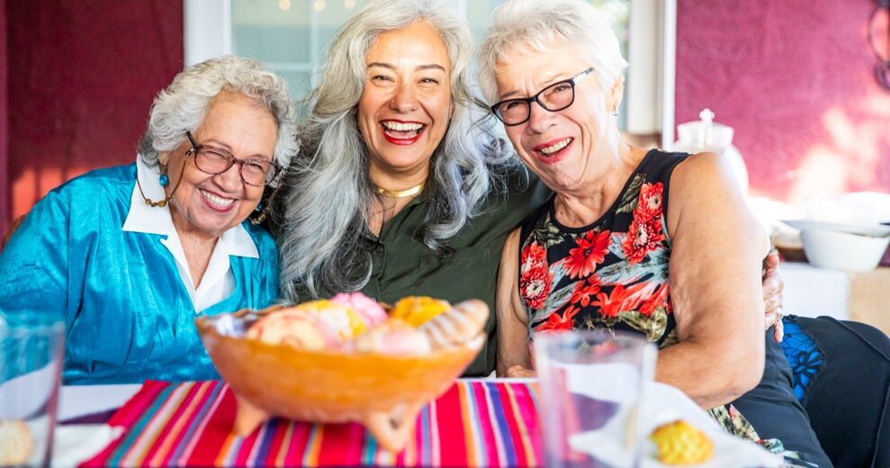 3happy older ladies sitting together a table enjoying chips and drinks