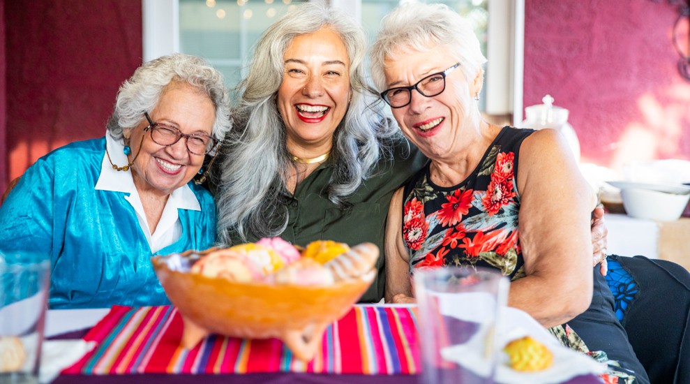 3happy older ladies sitting together a table enjoying chips and drinks