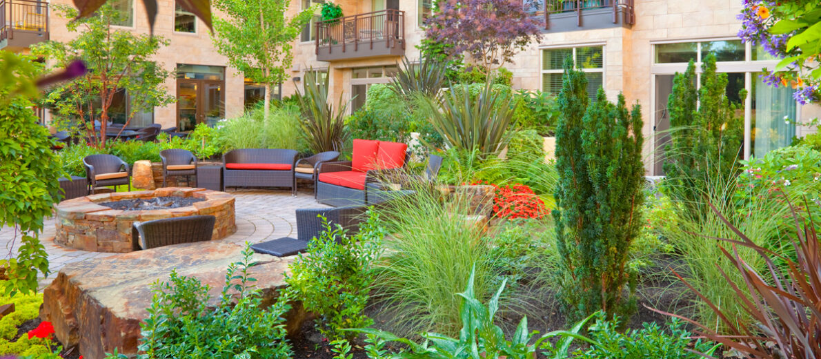 Inviting courtyard garden at the Aljoya Mercer Island, independent living and assisted living, retirement community, featuring lush landscaping, comfortable seating, water feature, and fire pit for seniors to relax and socialize outdoors in Mercer Island.