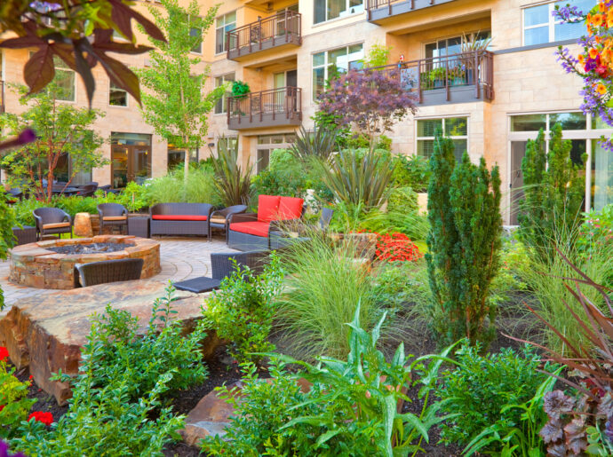courtyard garden view with lush landscaping, comfortable seating, water feature, fire pit, trees and big blue sky