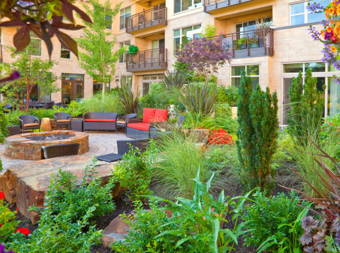 Inviting courtyard garden at the Aljoya Mercer Island, independent living and assisted living, retirement community, featuring lush landscaping, comfortable seating, water feature, and fire pit for seniors to relax and socialize outdoors in Mercer Island.