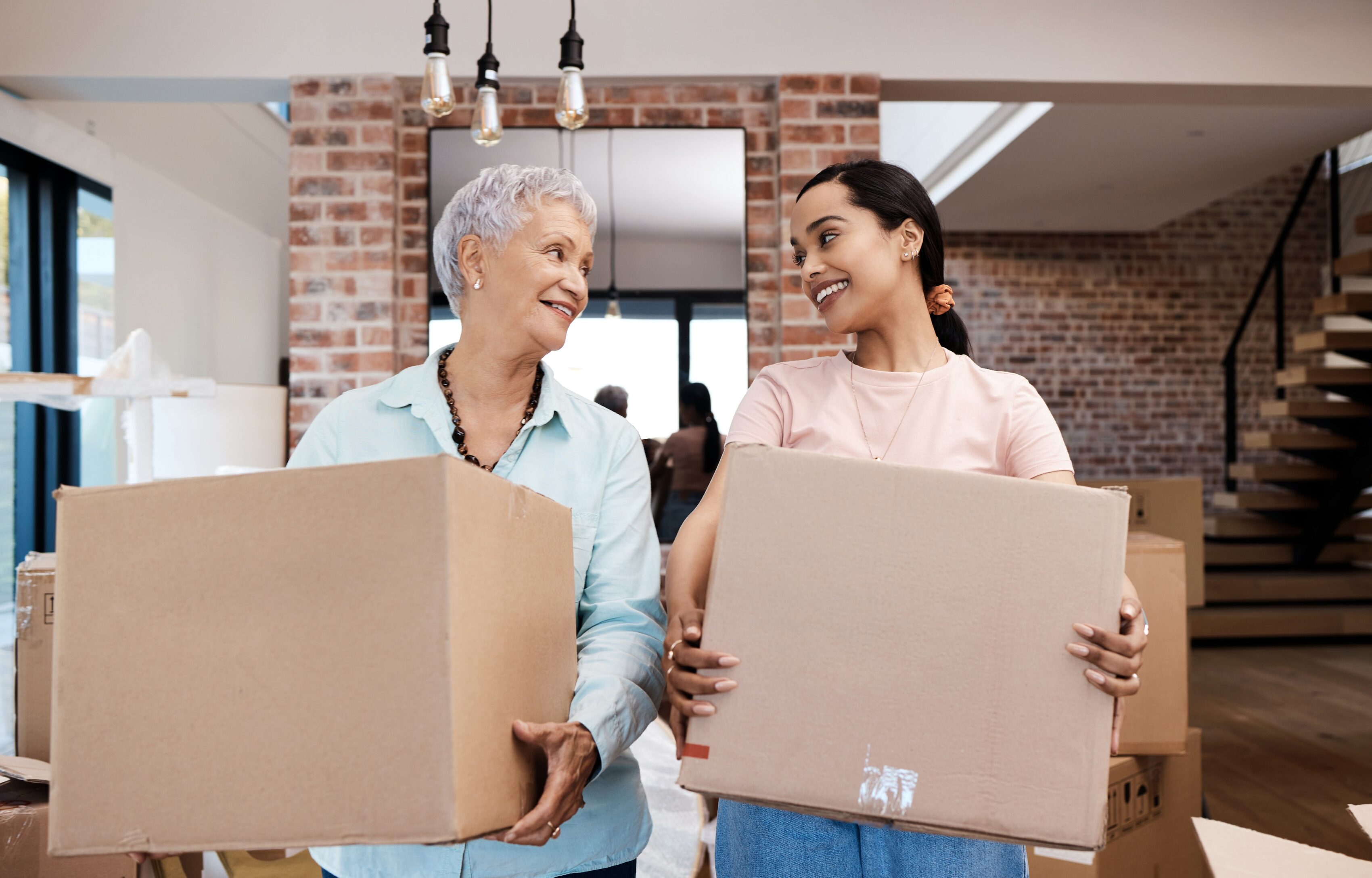 Grandma and her granddaughter in a living room holding moving boxes and working on downsizing