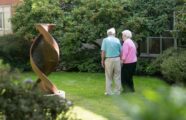 Elderly couple holding hands, walking in courtyard