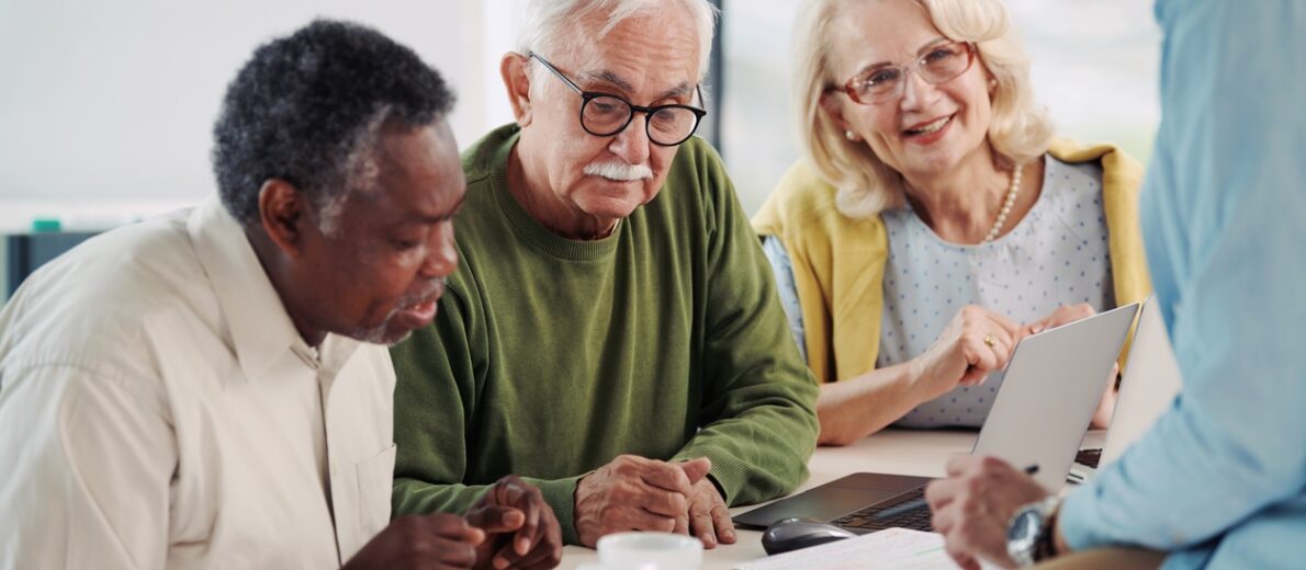 3 older adults researching on a laptop