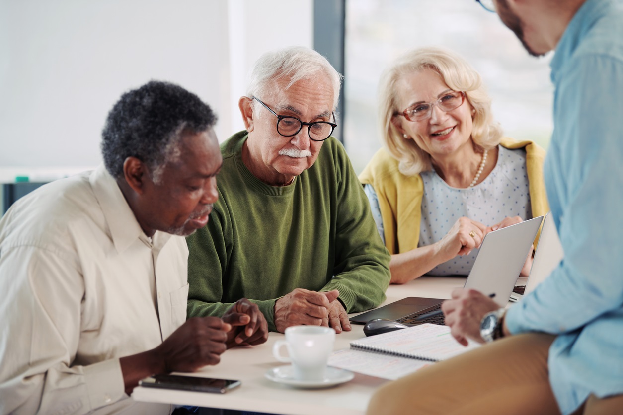 3 older adults researching on a laptop
