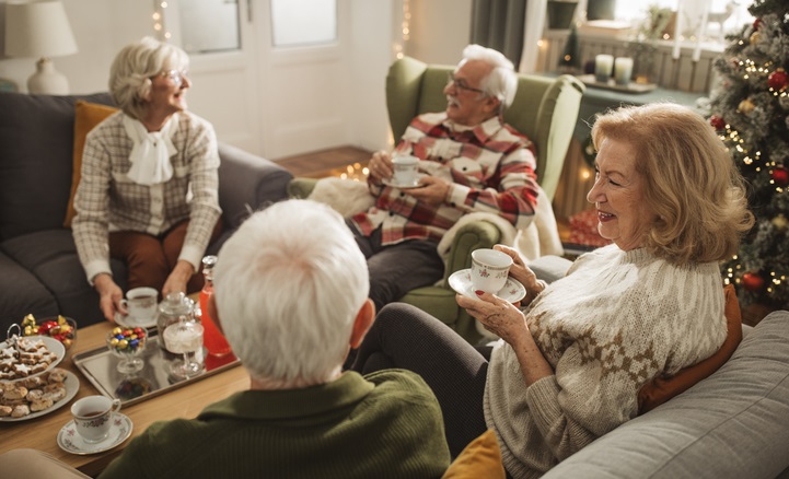 Holiday Open Hoise with 2 older couples sitting at coffee table with Christmas tree in background