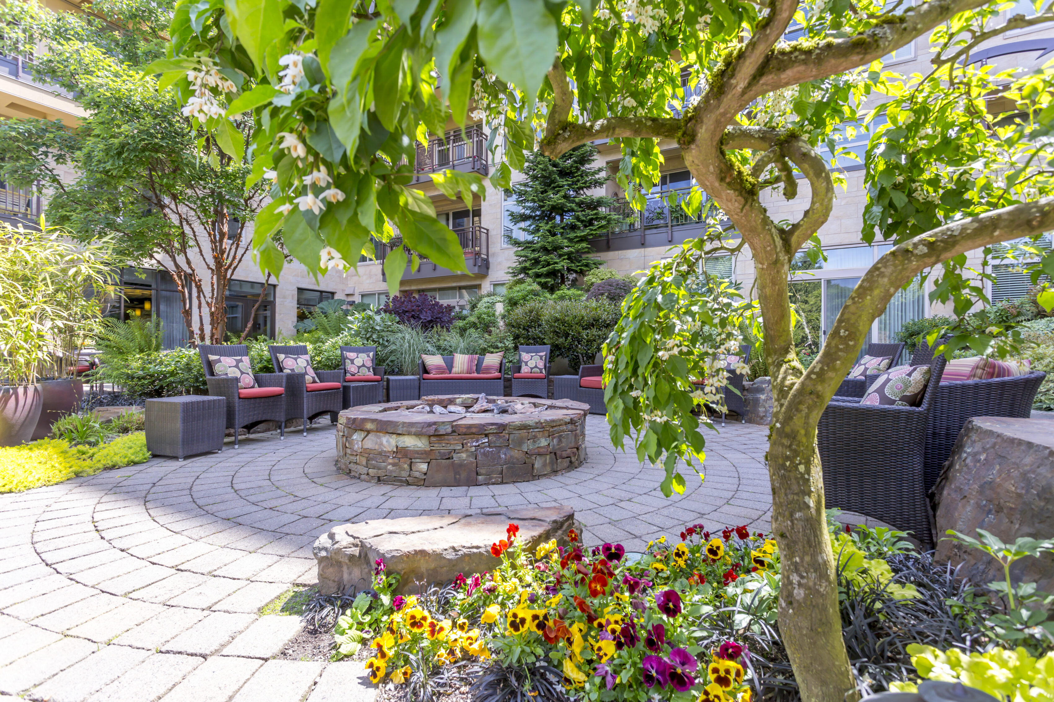Serene outdoor garden courtyard at the Aljoya Mercer Island retirement community in Mercer Island, featuring a fire pit, comfortable seating, and lush greenery for relaxation.