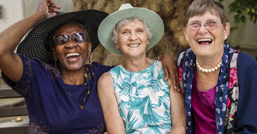 3 senior women laughing together at a garden party