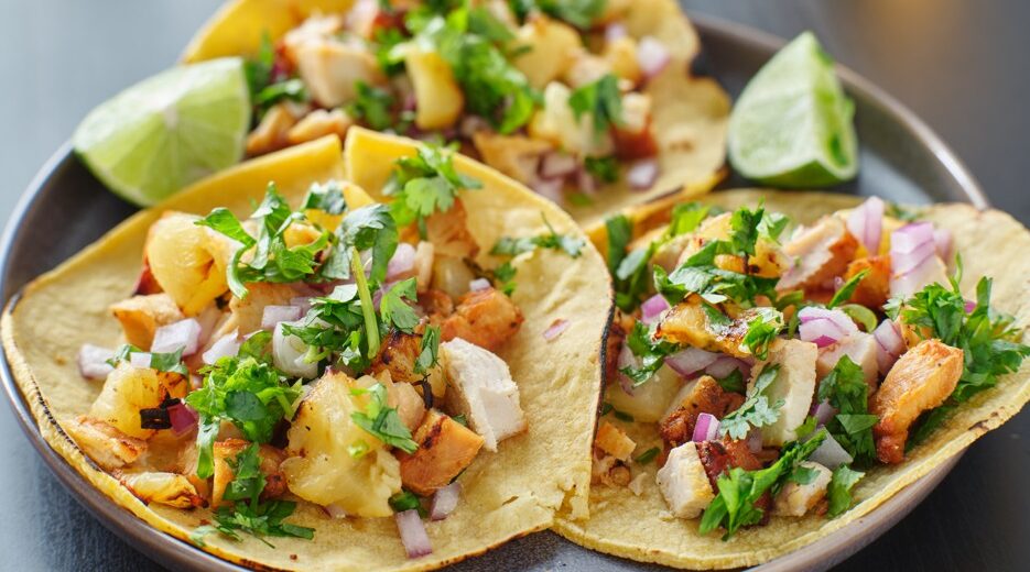 A close up of 3 mahi-mahi street tacos with pinapple salsa