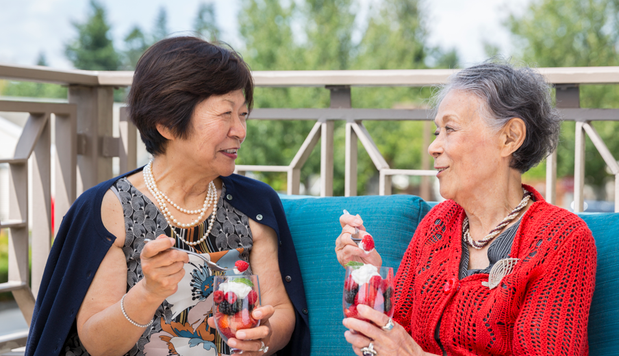 Two older ladies sitting outside enjoying ice cream.