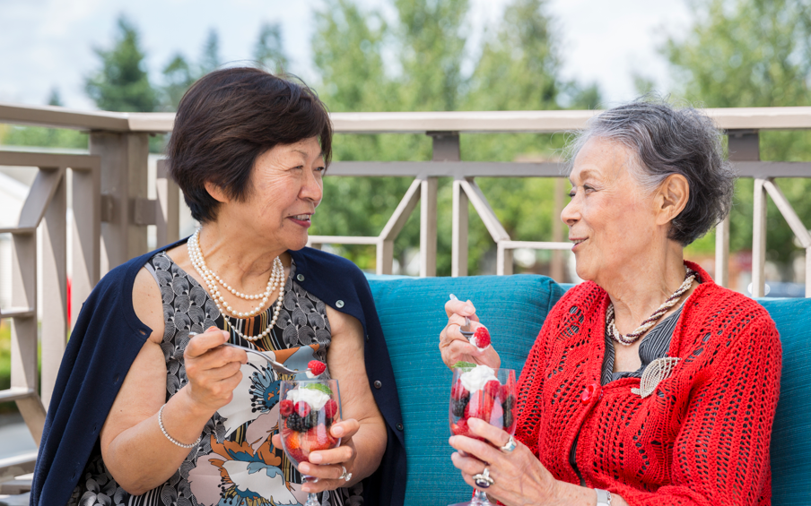 Two older ladies sitting outside enjoying ice cream.