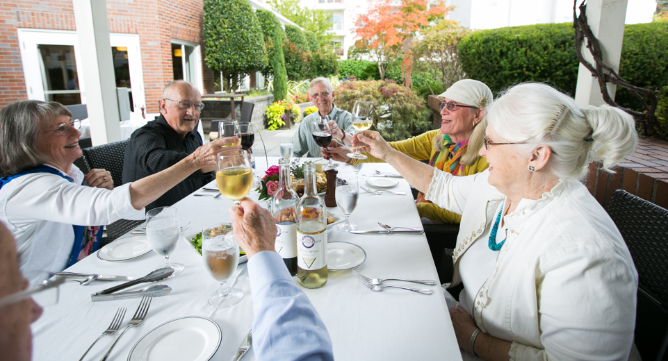 A group of happy senior adults sitting at a table in the garden.