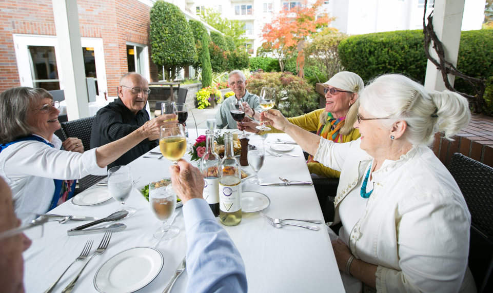 A group of happy senior adults sitting at a table in the garden.