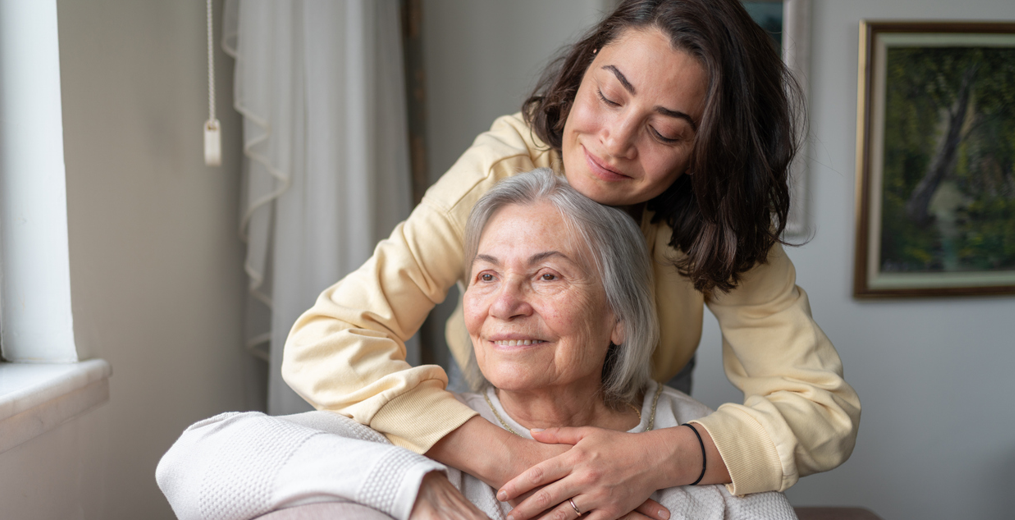 A younger woman gently hugging an older woman