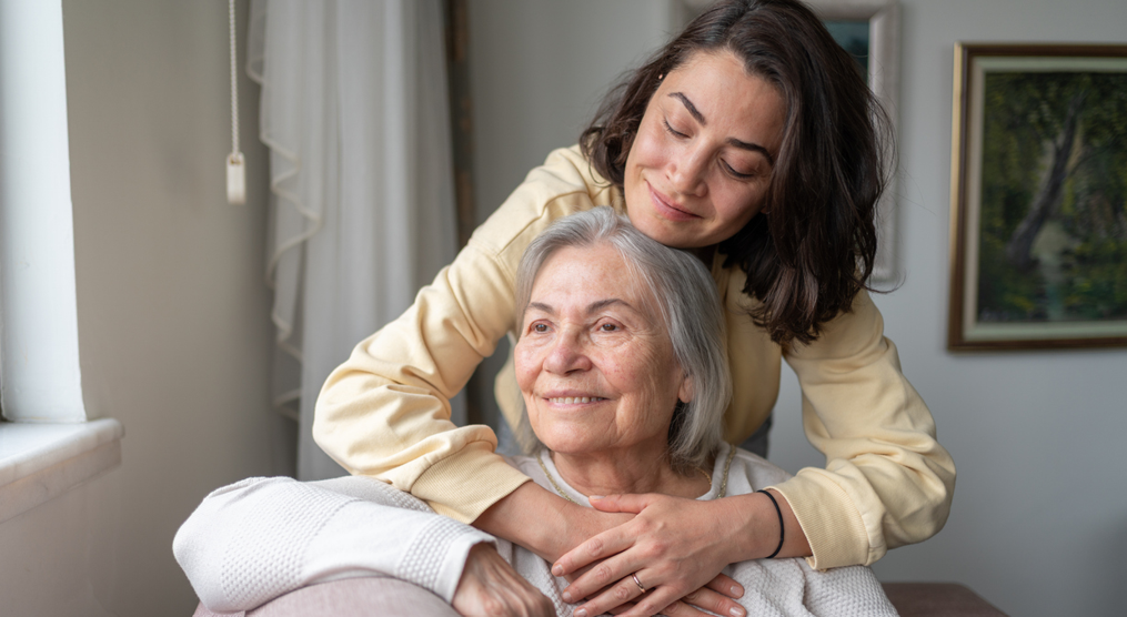 A younger woman gently hugging an older woman