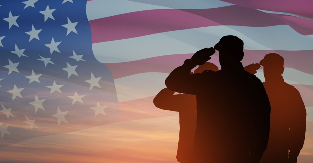 Sillouette of 3 veterans saluting the American Flag